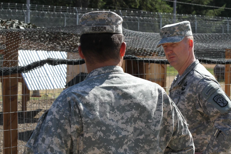 two military men in uniform stand at the fence of a park