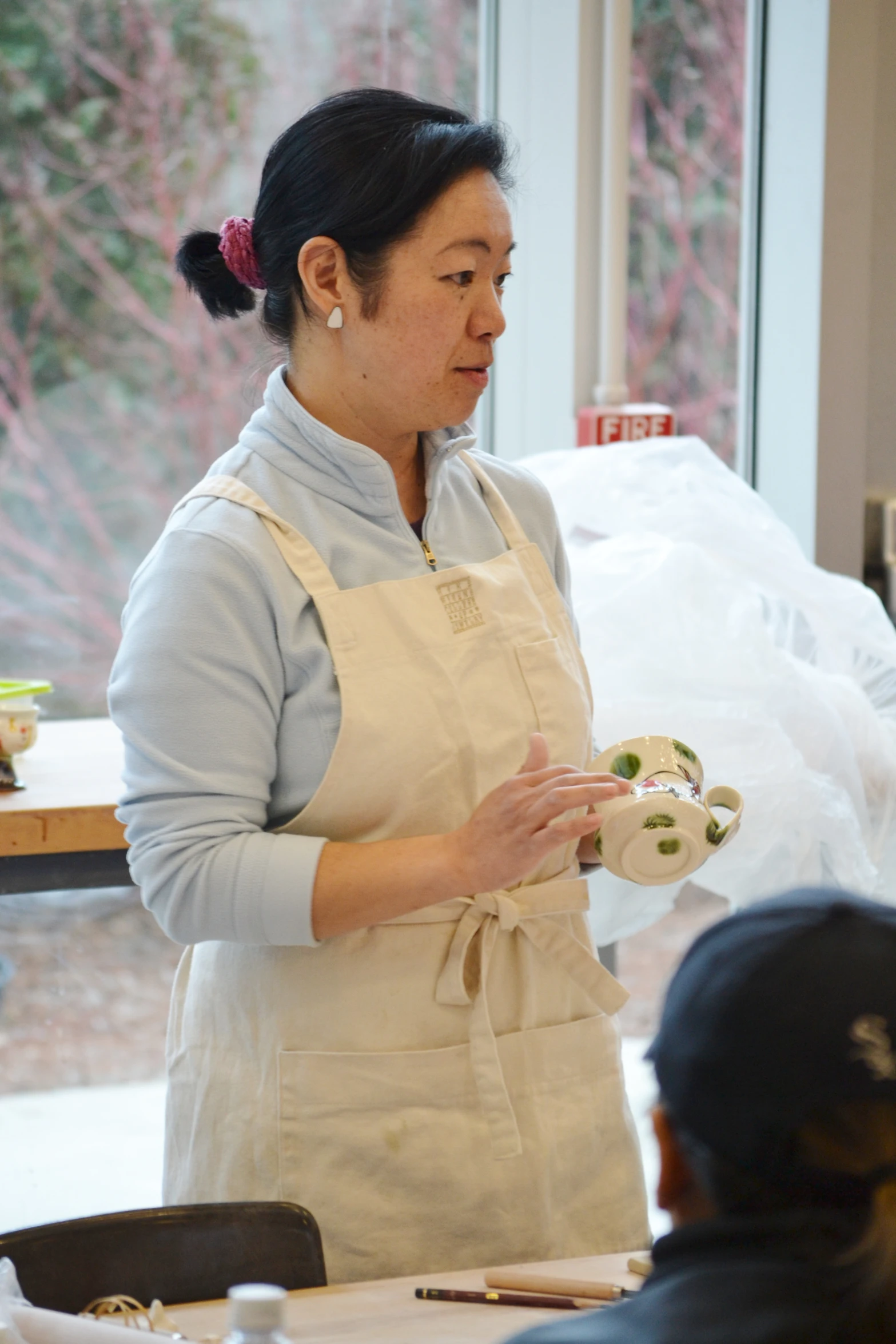 an asian woman wearing an apron while holding food