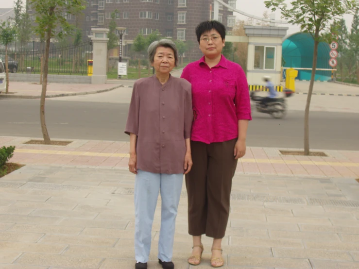 an older woman standing next to another woman on a sidewalk