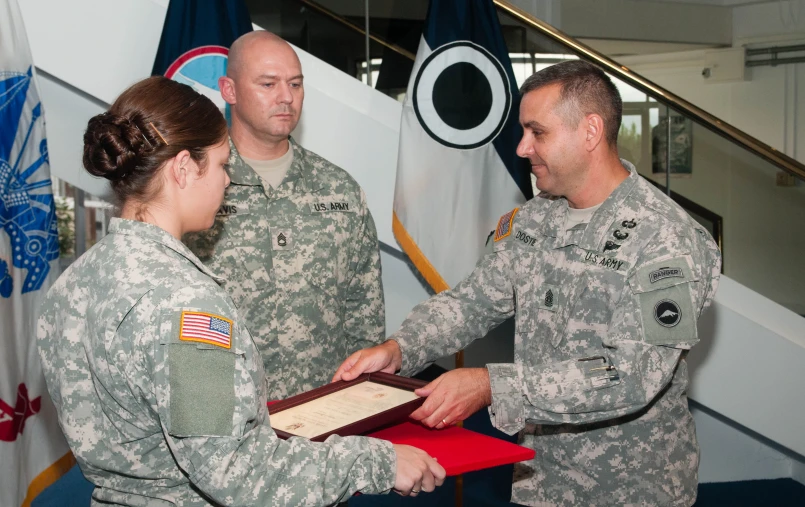 military woman receiving a card from a man in uniform