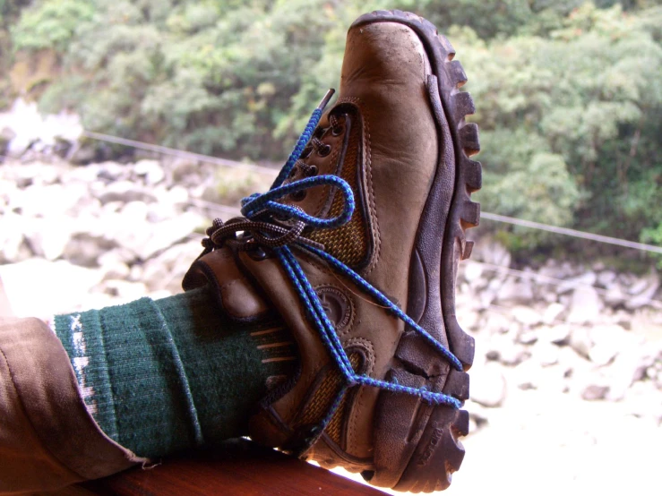 shoes with blue rope are tied up next to a rock covered river