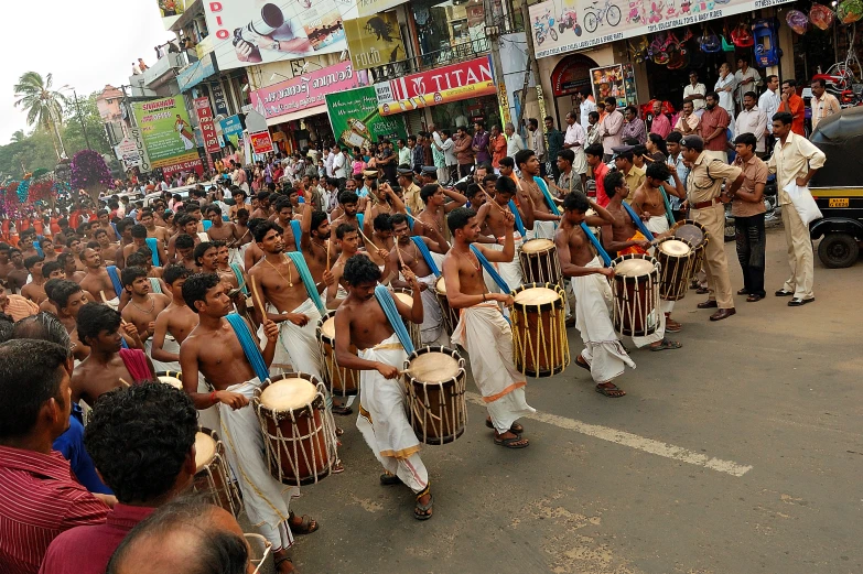 men in different colored outfits holding drums on street