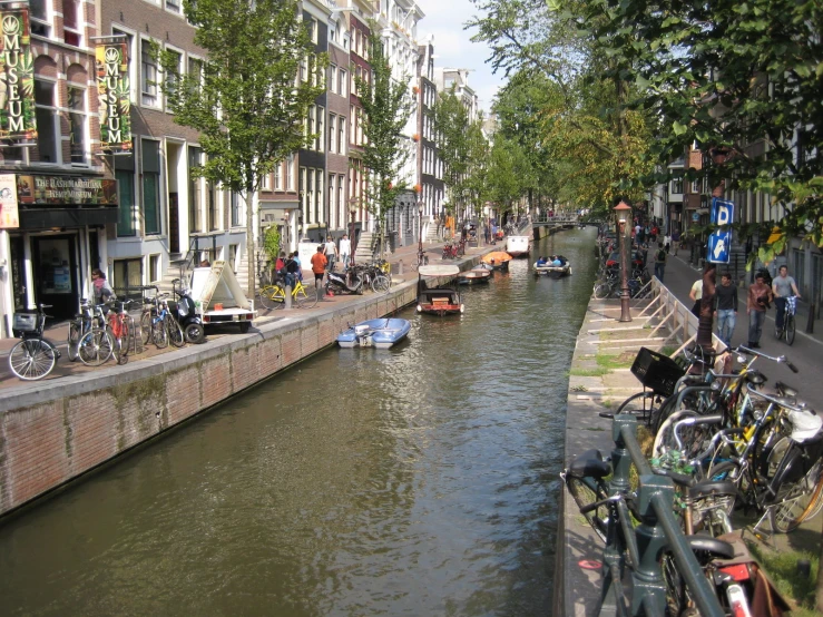 boats lined up on a river as people walk down the bridge