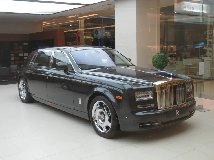 a black rolls royce parked in front of a glass building