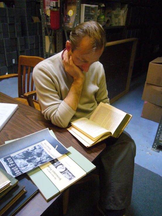 a man sitting at a table with an open book in his hands