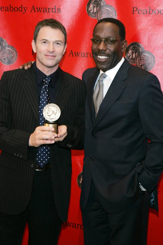 two men posing for the camera with an award