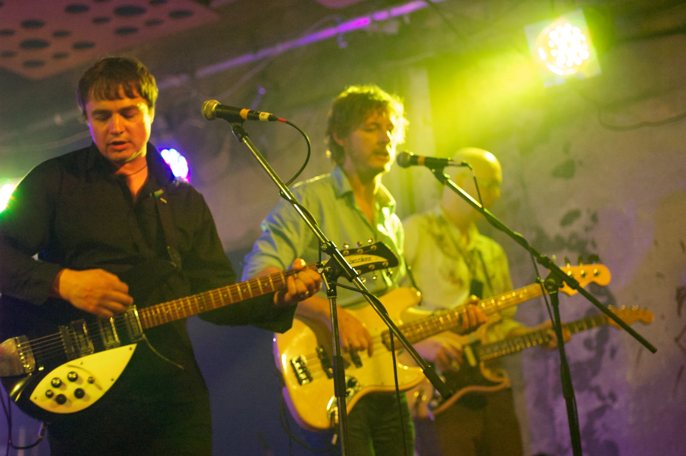 a man standing next to another man holding an electric guitar