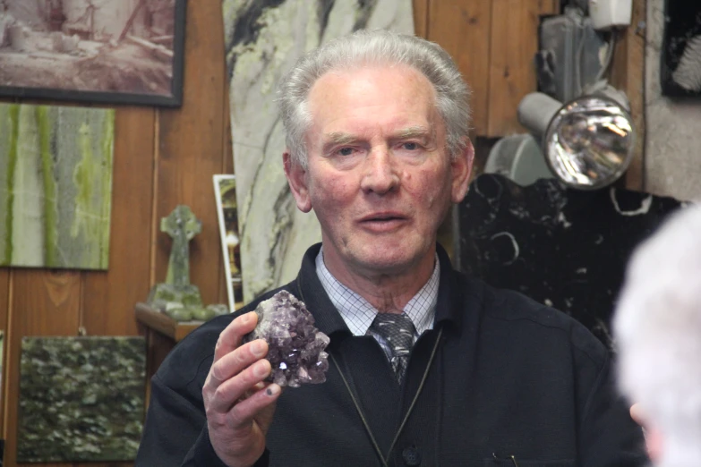 a man holding a piece of glass with other items in the background