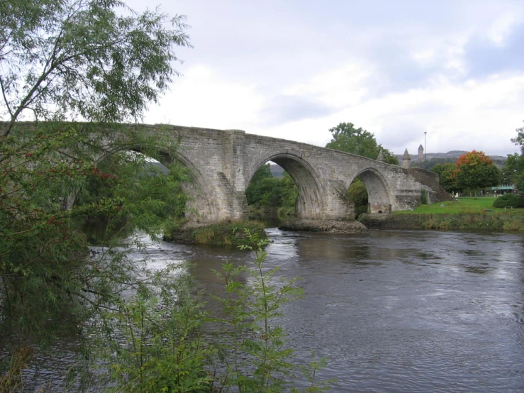 a stone bridge over a river on a cloudy day