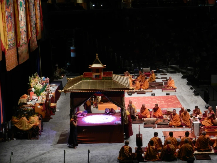 men in orange clothes sit around with one man speaking