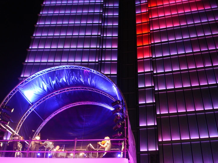 the large and brightly lit arch is near a tall building