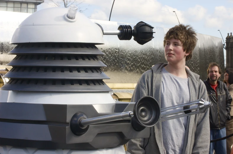 a boy holding a metal rod is standing next to the tardish