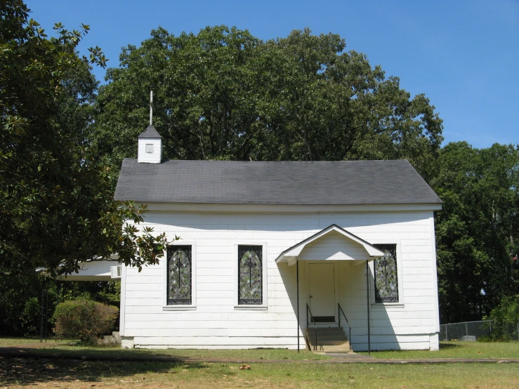 a small building with a roof with a steeple is sitting outside of the house