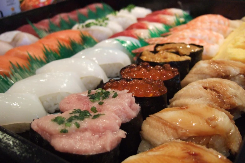 a variety of sushi on a black tray