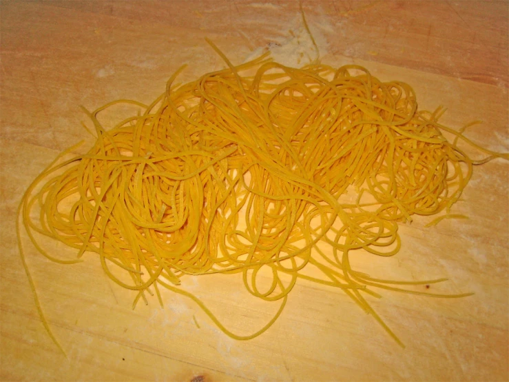 the yellow colored pasta is on the wooden table
