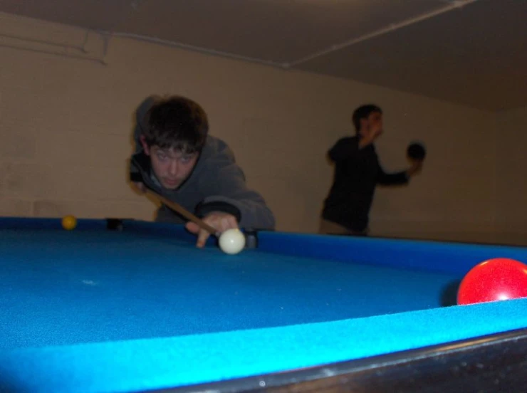 two guys are playing pool with their balls