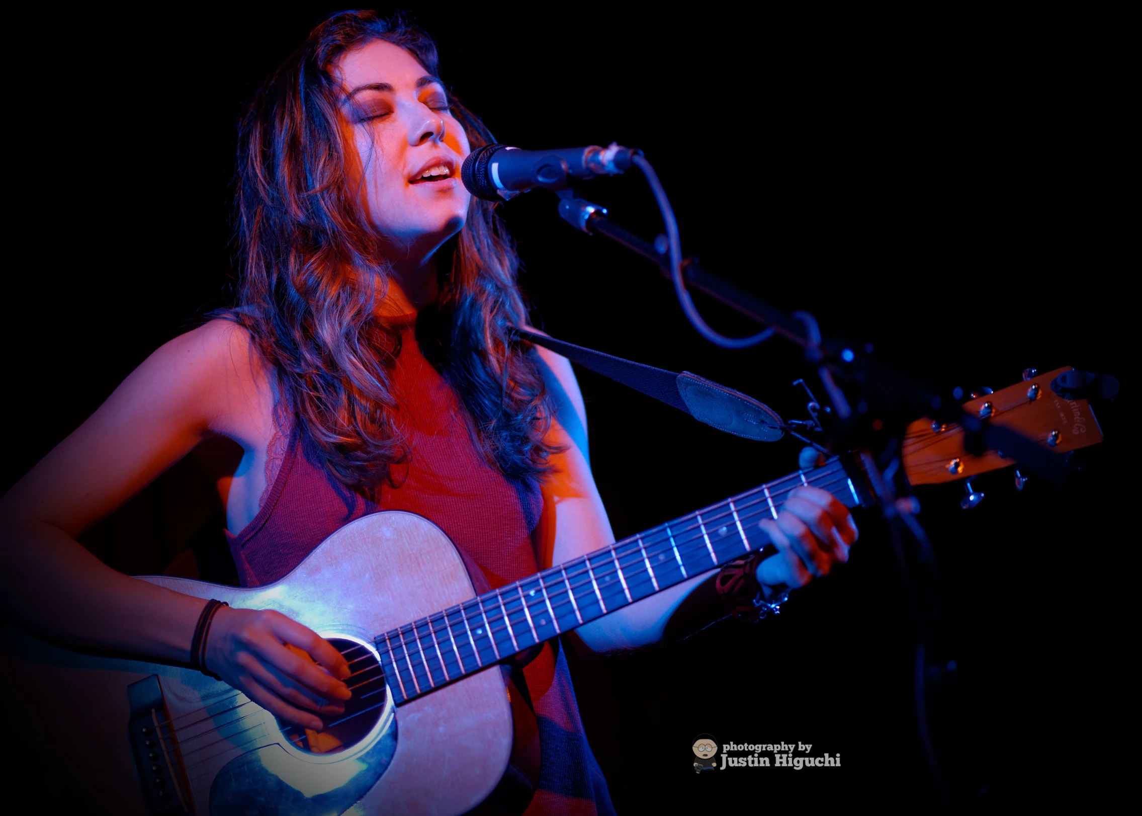 woman playing the guitar in front of a microphone