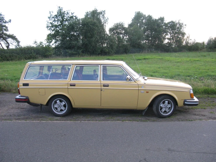 the yellow station wagon is parked by the side of the road