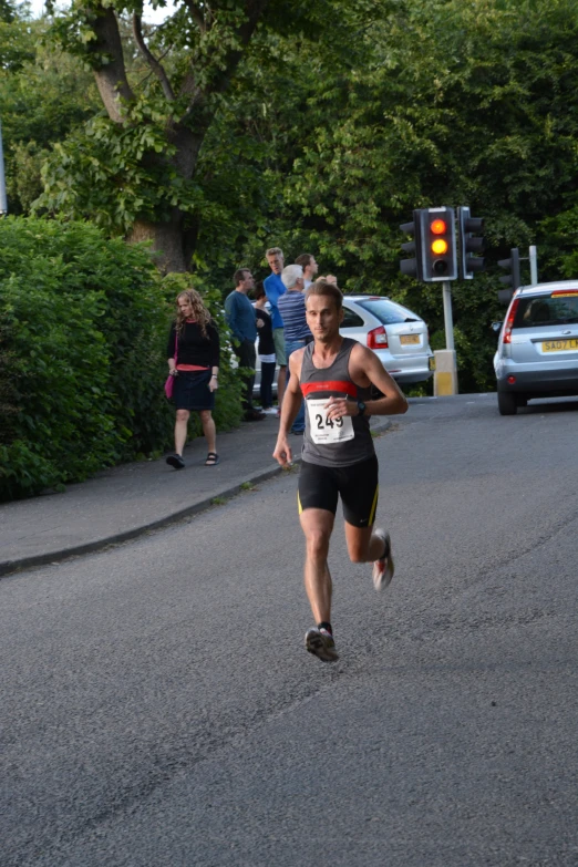 a young man running on the road while a group of people watch