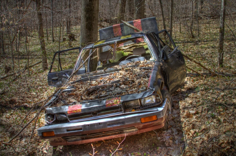 an old, damaged car in the middle of a woods