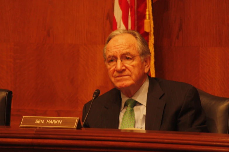 the man is seated at the wooden desk