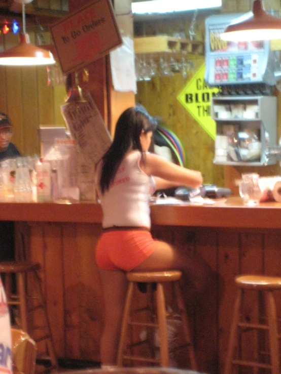 a girl sitting at the bar using a cellphone