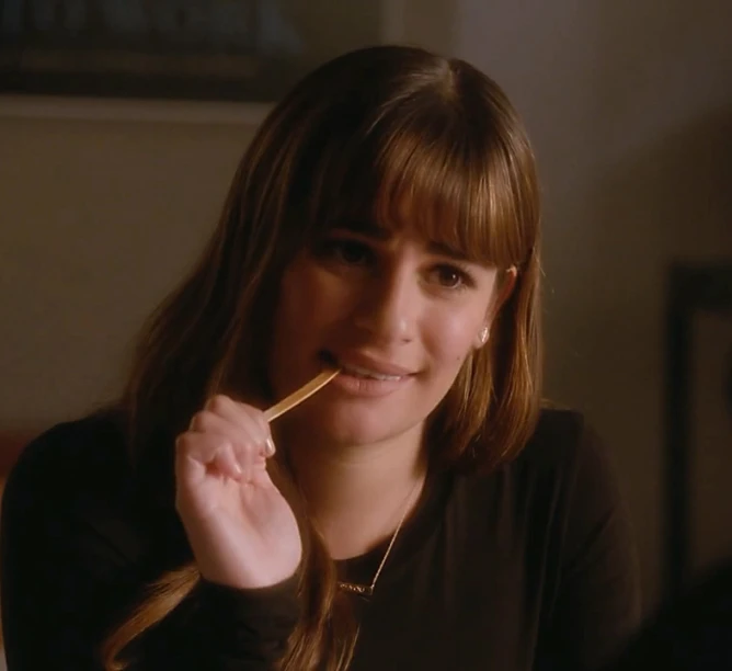 a woman looking at the camera while brushing her teeth