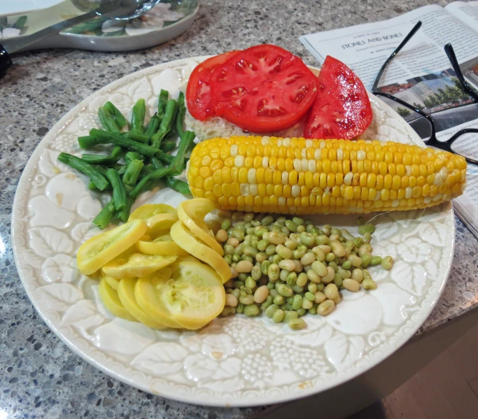 a plate with corn, beans, tomatoes, tomatoes, and cucumbers