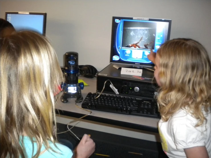 two girls looking at the same monitor and playing games