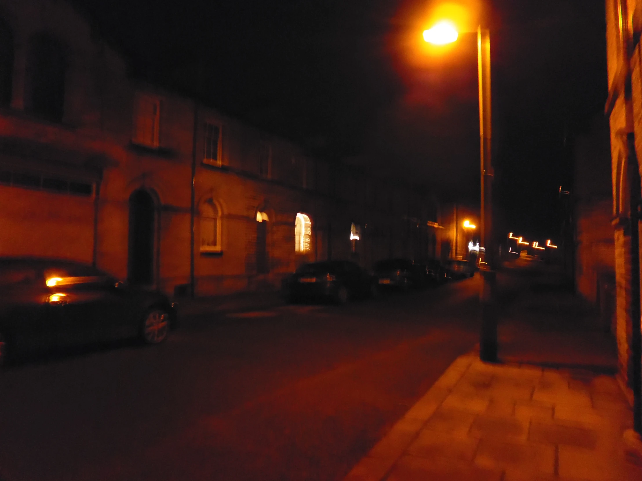 an image of the side of an old building with traffic going by at night