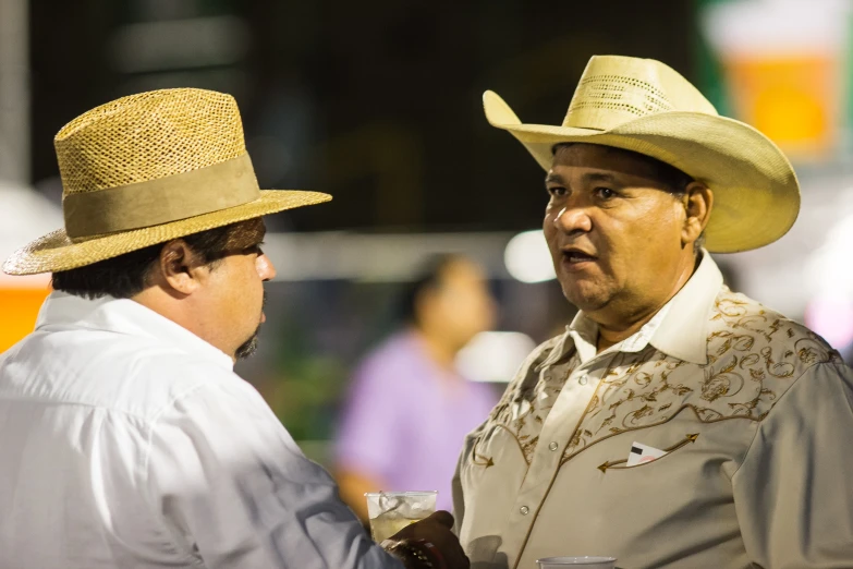 two men with hats on talking and one man is holding soing