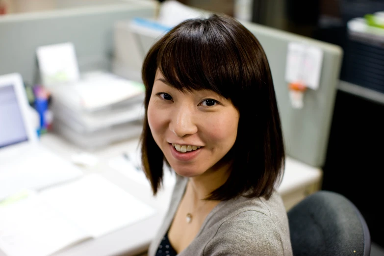 a woman smiling at the camera while sitting in an office chair