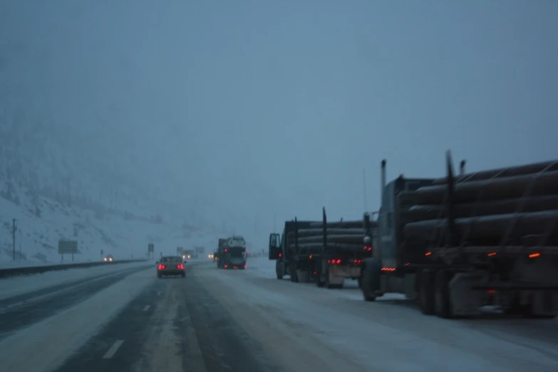 traffic on a snowy highway with some trucks driving down the road