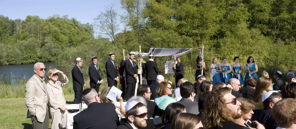 the people are standing on a lawn, holding signs