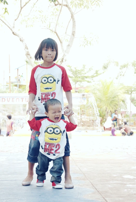 two young children pose with one wearing a shirt that has an angry minion on it