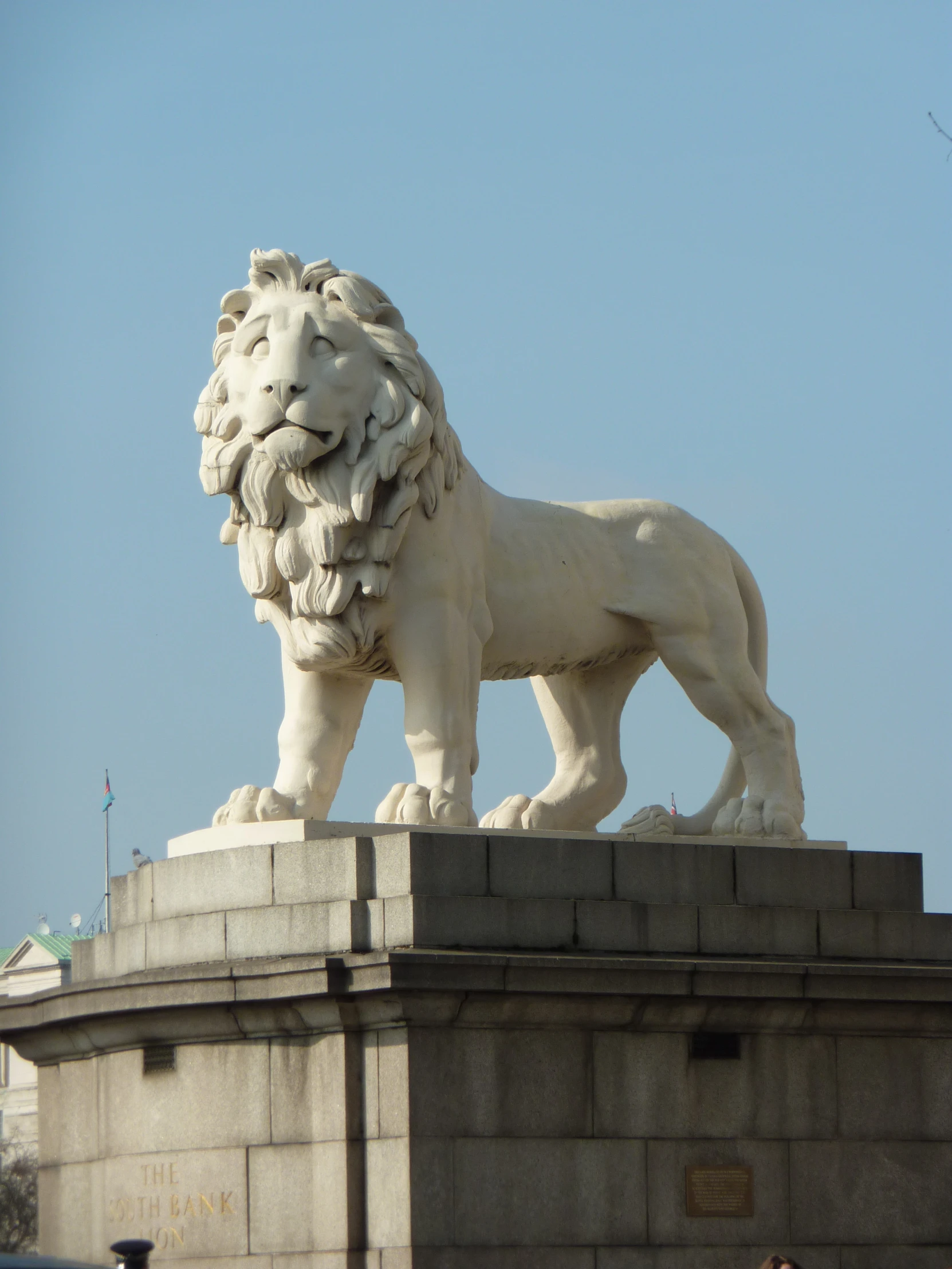 a stone lion statue atop a building, on a sunny day