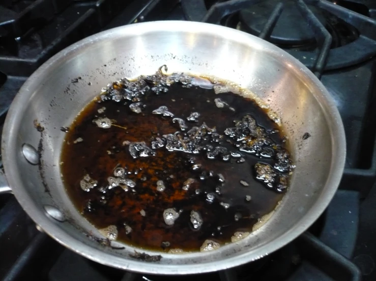 a metal pan filled with sauce sitting on top of an oven