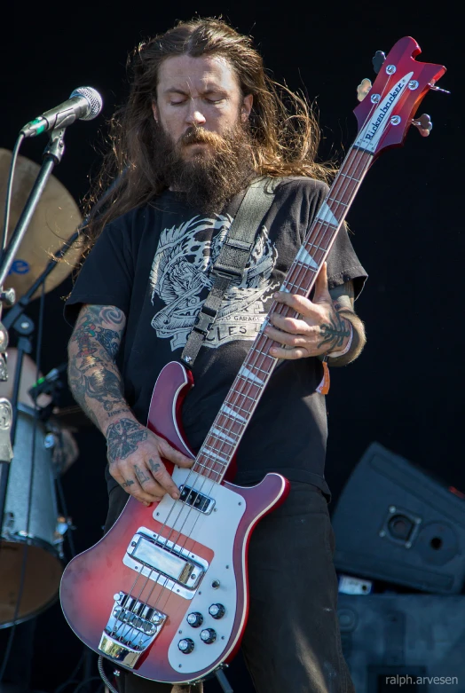 a man with long hair and a beard plays an electric guitar