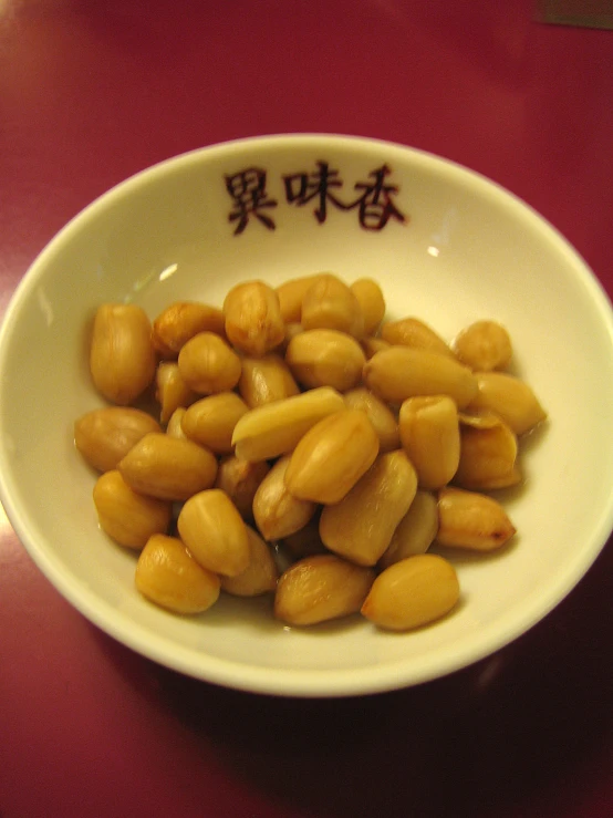 a bowl of beans sits on a red surface
