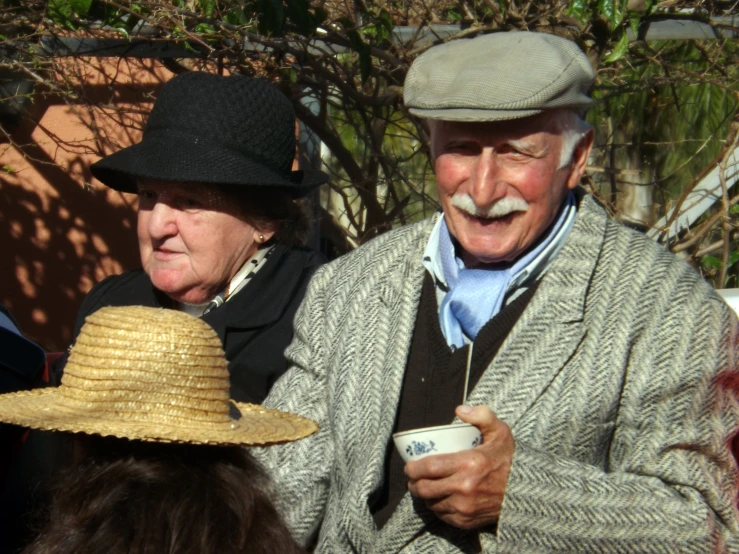 an older man is holding a coffee cup with another older woman next to him