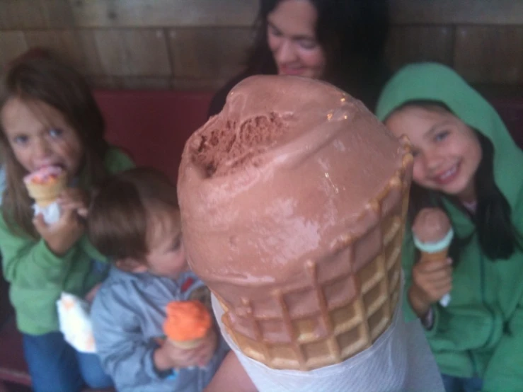 a girl in a green jacket eating an ice cream cone