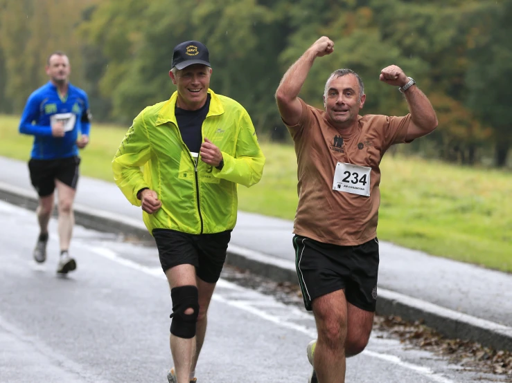 some runners in the rain runing on a street