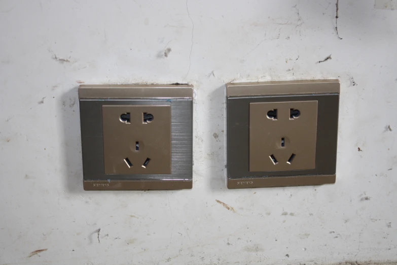 two silver square electrical outlets in a white walled wall