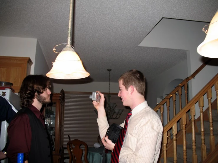 two men standing in a kitchen with one taking a picture