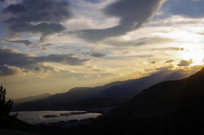 the sun rises on top of a mountain, overlooking water and mountains