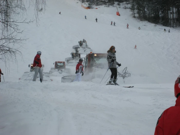 many people standing in the snow with some skis