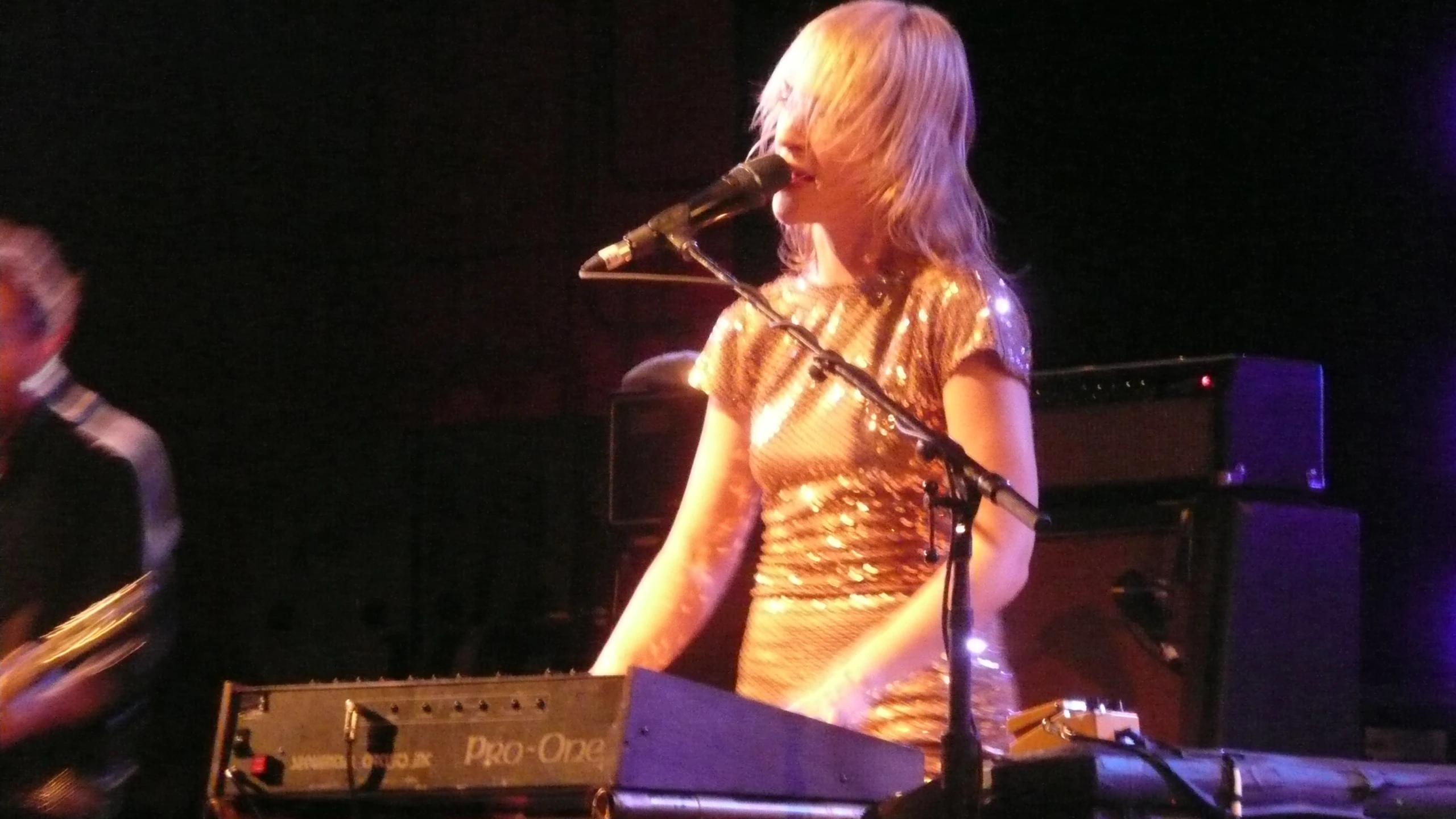 two women singing on stage while playing keyboards and a guitar