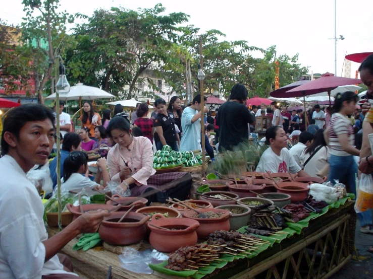 many people are standing outside near an outdoor market