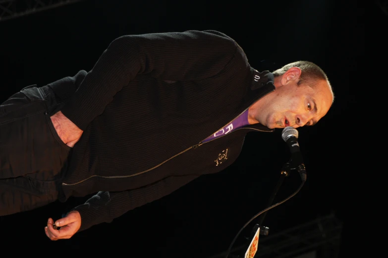 a man is performing at the microphone in a concert