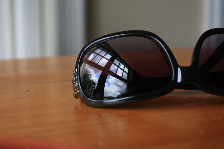 a pair of sunglasses is on the table with a reflection in it